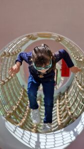 Child climbing through a rope tunnel at a playground in Canton Zug